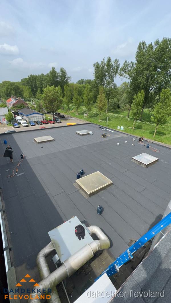 Dakdekker aan het werk op groot plat dak met bitumen in Flevoland Dakdekker aan het werk op groot plat dak met bitumen in Flevoland