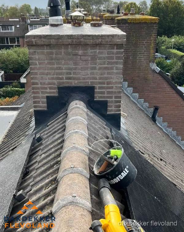 Schoorsteen met loodaansluiting en nokvorst op pannendak in Flevoland