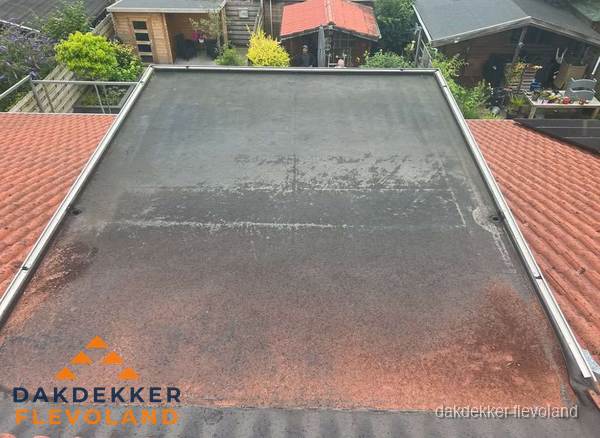Verouderd plat dak met slijtage tussen schuine daken in Flevoland Verouderd plat dak met slijtage tussen schuine daken in Flevoland