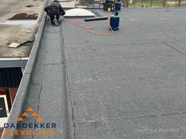 Dakdekker repareert bitumen dakbedekking op groot plat dak in Flevoland Dakdekker repareert bitumen dakbedekking op groot plat dak in Flevoland
