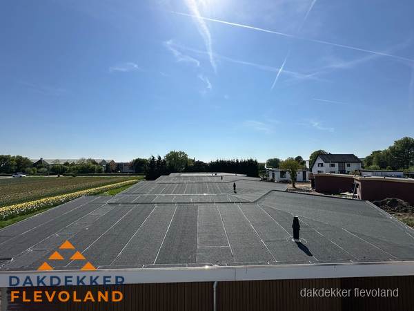 Groot plat dak met bitumen dakbedekking op bedrijfspand in Flevoland Groot plat dak met bitumen dakbedekking op bedrijfspand in Flevoland