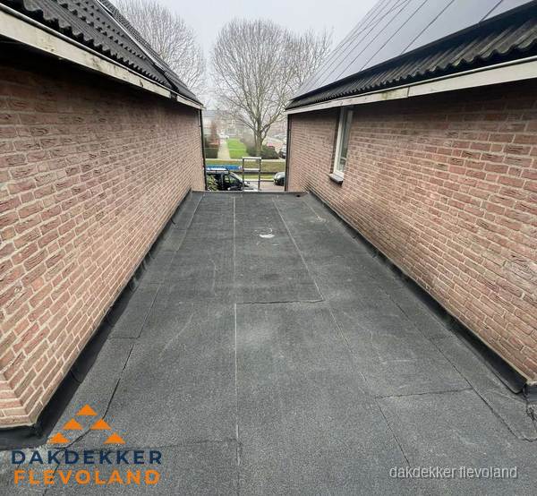 Plat dak met bitumen dakbedekking tussen bakstenen muren in Flevoland Plat dak met bitumen dakbedekking tussen bakstenen muren in Flevoland